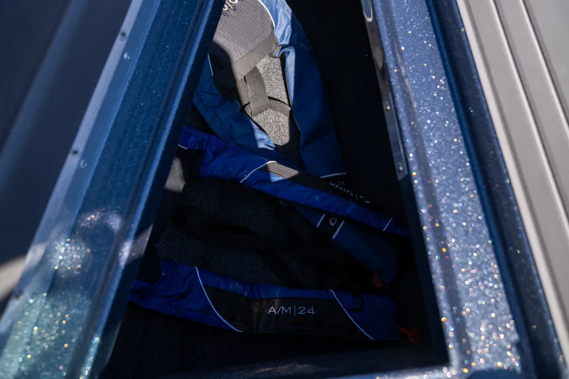 Open side storage compartment holding folded blue and black life jackets.