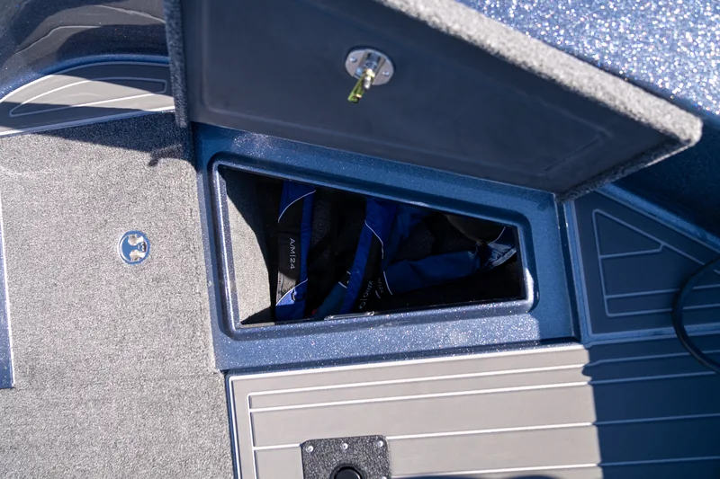 Open under-seat storage compartment with life jackets inside, seen from above with the hatch lid raised.