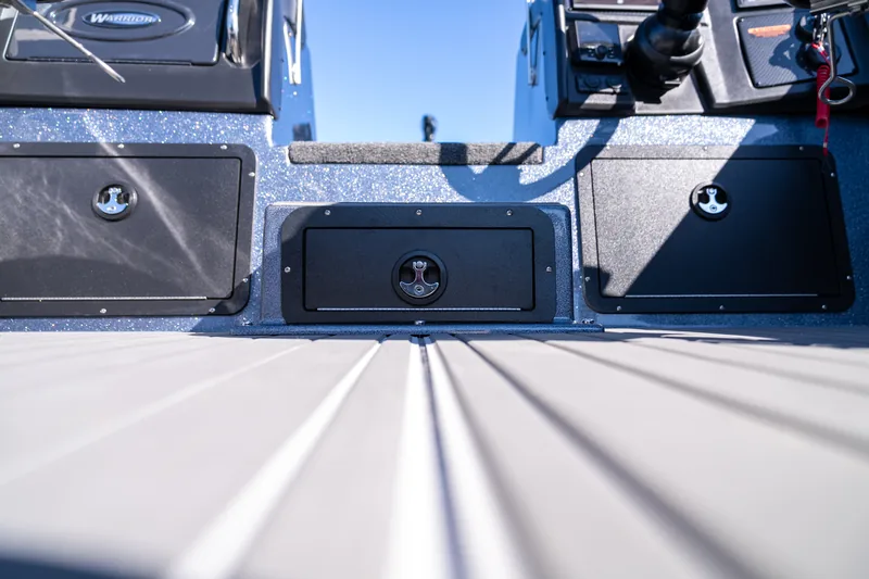 A latched black bilge access door in the transom wall flanked by two larger storage hatches above the deck.