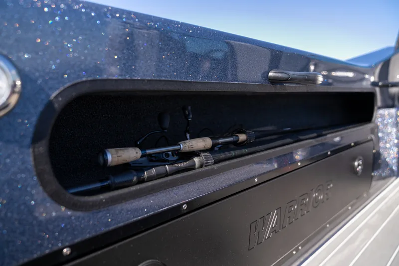 Open side rod locker along the gunwale holding two fishing rods in a carpeted channel.