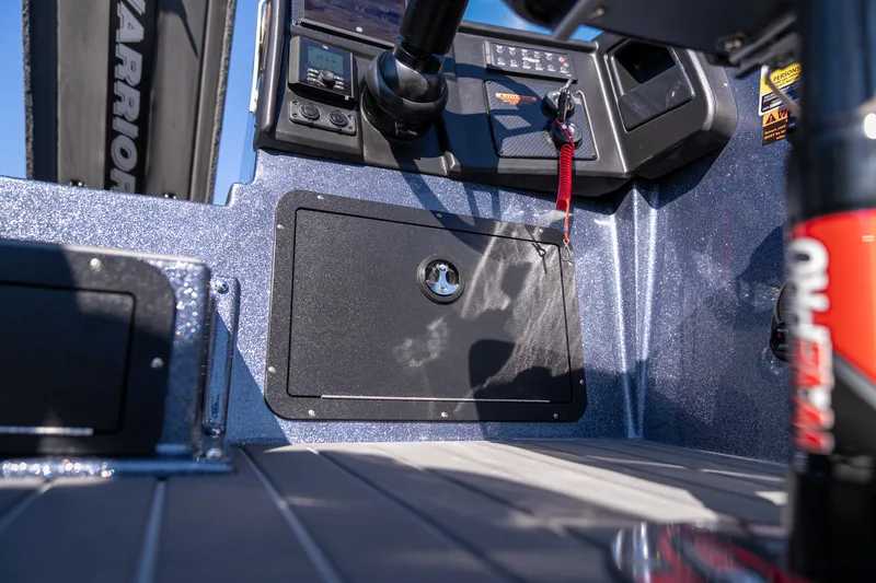Closed black latching glove box panel below the console with the kill switch lanyard hanging above.