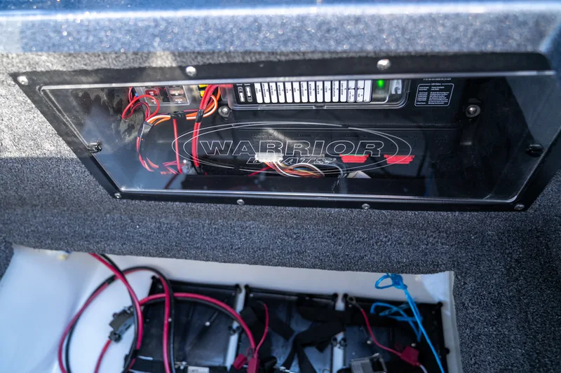 Onboard battery charger mounted behind a hatch with battery cables and a battery tray visible below.