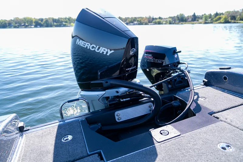 The transom of the boat on the water showing a large Mercury outboard and a smaller kicker motor.
