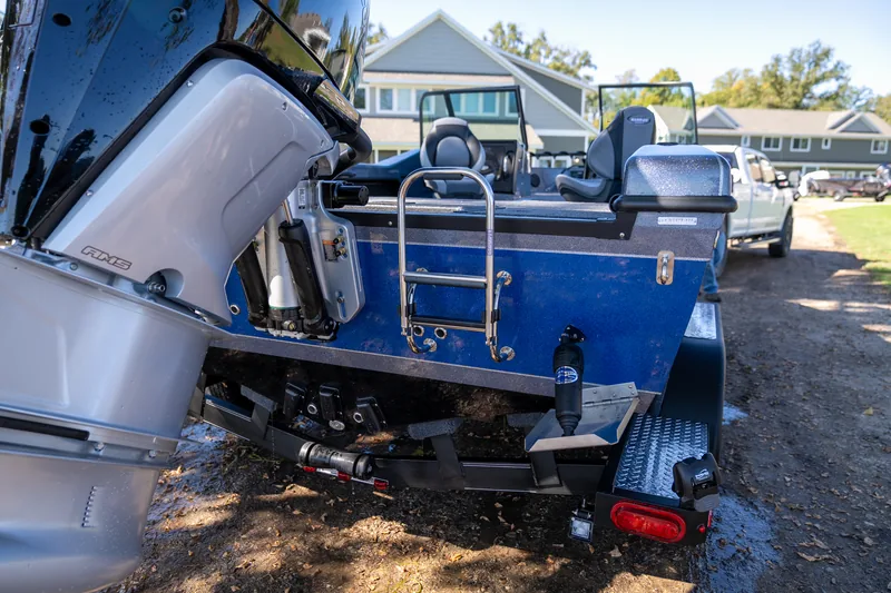 The stern of the trailered boat with the outboard tilted up and a stainless boarding ladder mounted on the transom.