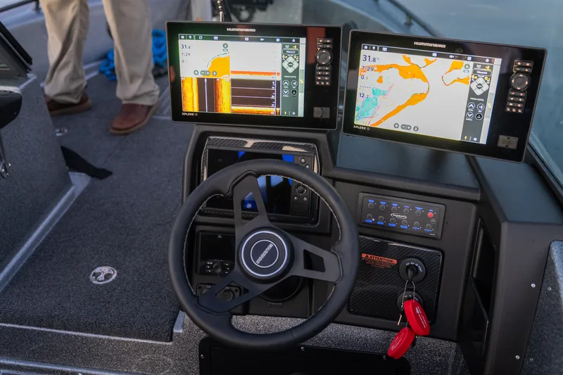 Boat helm with steering wheel, two large Humminbird display screens, switch panel and ignition key.